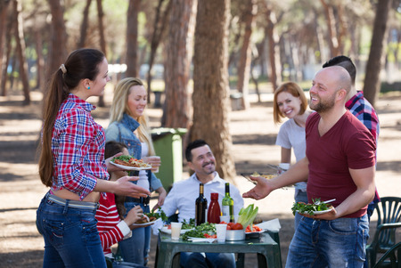 Happy young friends relaxing at grill party in sunny dayの写真素材