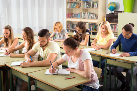 Students sitting at their desks in a classroom and studying thoroughlyの写真素材