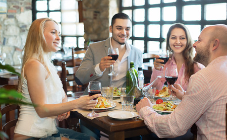 Positive happy young people enjoying food and smiling in the tavernの写真素材