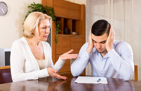 Sad senior woman and young boyfriend with invoices for paymentの写真素材