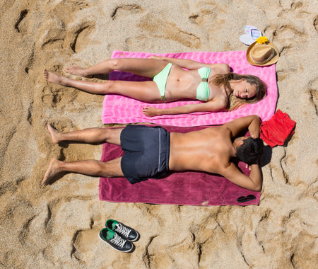 Young  smiling  lovers sunbathing at sandy beach in honeymoon