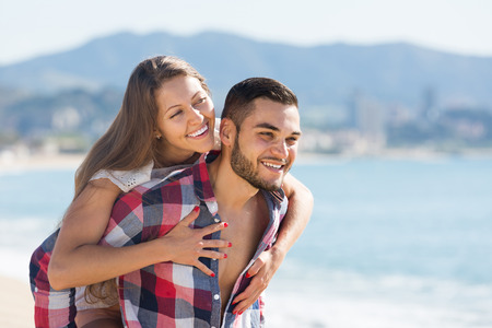 young smiling couple spending free time at seaside in summer dayの写真素材