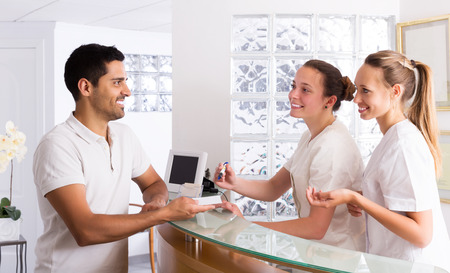 Happy young man talks with nurses in the medical officeの写真素材