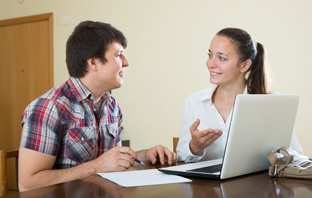 Girl talks with young european man while interviewing him at homeの写真素材