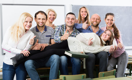Happy female professor and cheerful students posing in classroom at extension courses