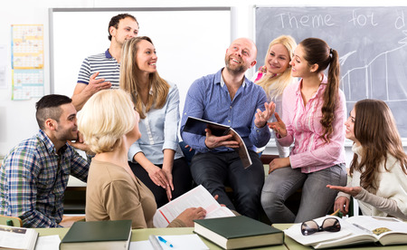 Charming language teacher is telling interesting stories to his attentive students during a break in a classroomの写真素材