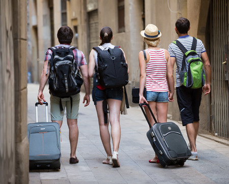 Group of friends tourists walking at the street with luggageの写真素材