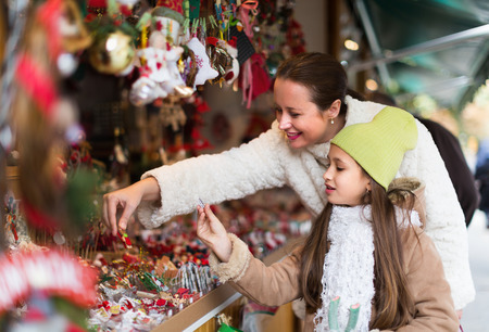 Smiling mother with positive girl in Christmas market. Focus on girlの写真素材