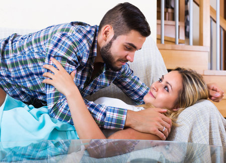 Portrait of loving smiling couple on couch at home interior