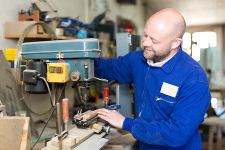 Professional carpenter using a boring mill to drill a hole in a piece of wood