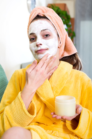 Portrait of a woman in a bathrobe in livingroom with a face mask on her faceの写真素材