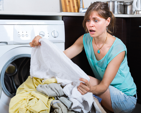 Upset maid looking at clothes with persistent stains after laundryの写真素材