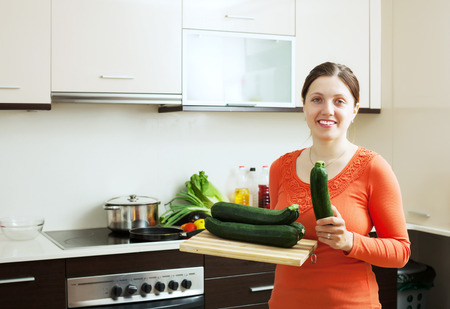 Young positive woman cooking with  vegetable marrowの写真素材