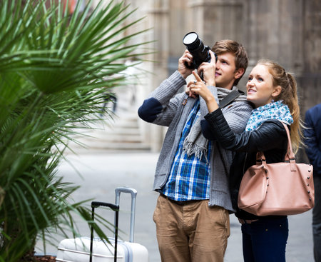 Young man and smiling girl with photo camera studying neighborhood. Focus on the woman