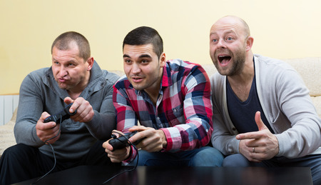 Three shouting friends playing computer games at house partyの写真素材