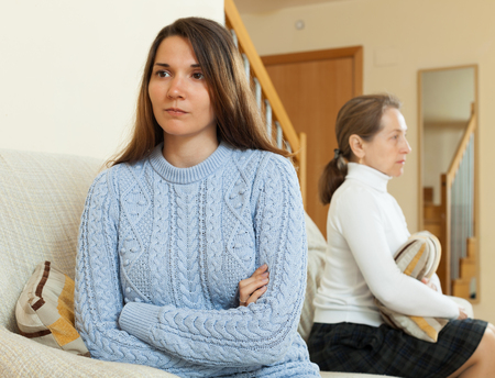 Serious  woman and teenage daughter after quarrel on sofa  in living roomの写真素材
