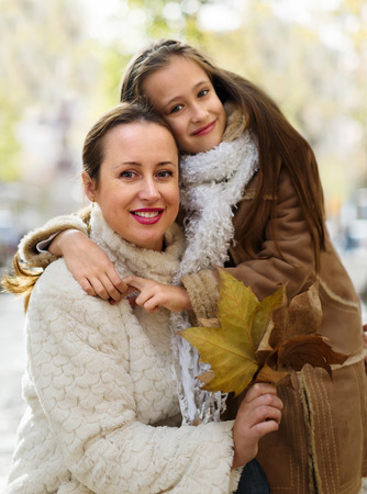 Happy woman with little daughter posing in november parkの写真素材