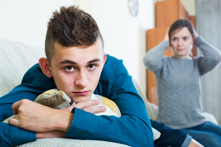 Frustrated mother scolding teenager son at home. focus on american boyの写真素材