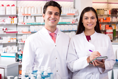 Portrait of two attracitve friendly pharmacists working in modern farmacyの写真素材