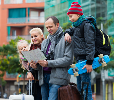 Happy middle class family of four checking the direction in a city mapの写真素材