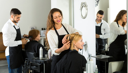 Hairdressers working on clients hair at a beauty salonの写真素材