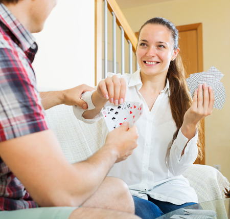 Young smiling couple playing cards and talking in homeの写真素材