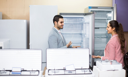 Happy european couple choosing new refrigerator in hypermarket and smilingの写真素材