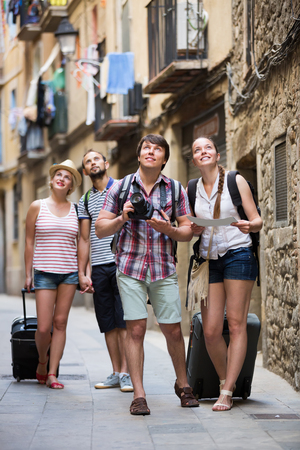 Group of positive tourists with camera and map walking at the streetの写真素材