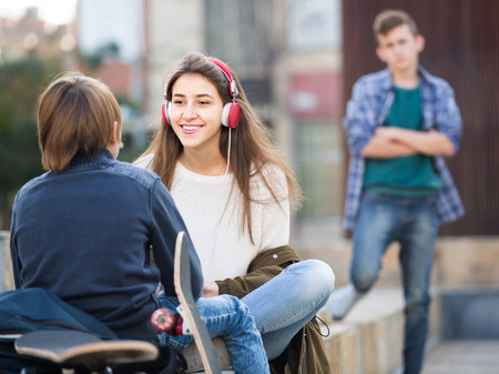 Jealous teen and his happy spanish friends after conflict outdoorsの写真素材