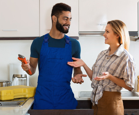 Specialist in uniform fixing leaky faucet, pleased cheerful  blondeの写真素材