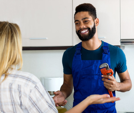 Cheerful girl thanking black professional plumber for workの写真素材