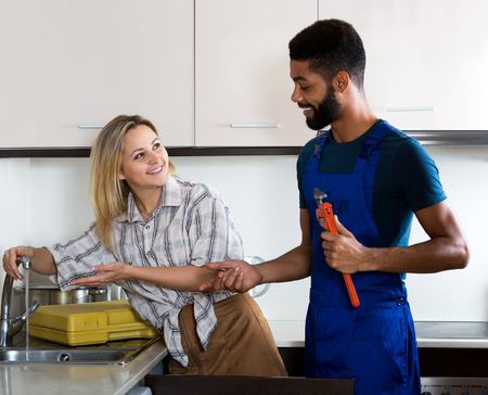 Attractive woman thanking black professional plumber for work. Focus on the womanの写真素材