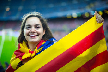 young female football fan with flag of Catalonia at stadiumの写真素材
