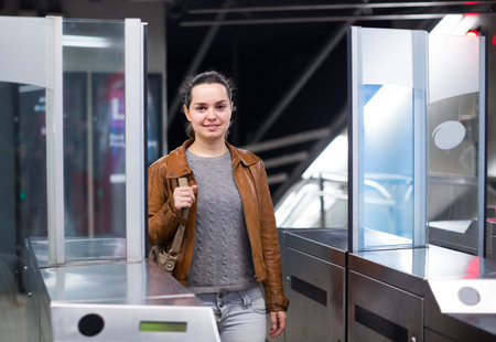Young woman passing the turnstile at subway station
