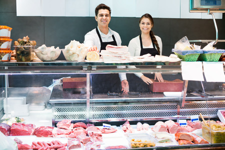 Delicatessen store staff selling fresh-killed a the meat and the saloの写真素材