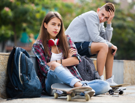 Teenager couple with the skateboards having an argue outdoorsの写真素材