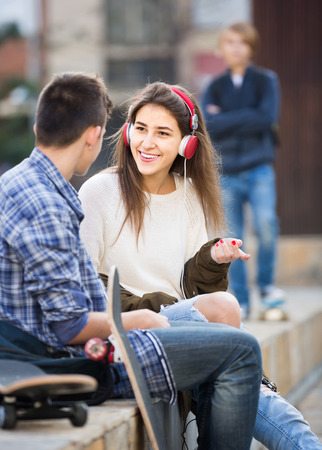 Jealous teen and his smiling friends after conflict outdoorsの写真素材