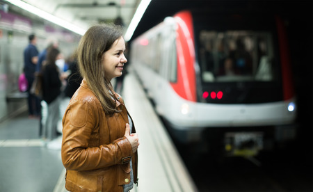 Charming brunette girl waiting for metro train and smilingの写真素材