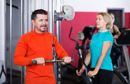 Adults of different age having strength training in gym