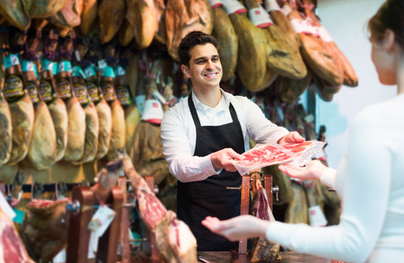 Young spanish brunette choosing iberico and serrano jamon and smilingの写真素材