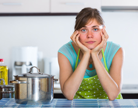 Portrait of tired young housewife at home kitchenの写真素材