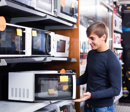 Handsome guy selecting microwave oven in hypermarket and smilingの写真素材