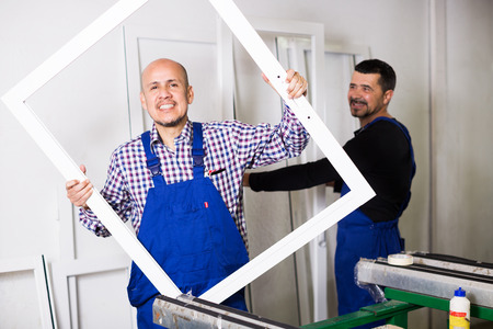 Professional workmen with finished PVC profiles and windows at factoryの写真素材