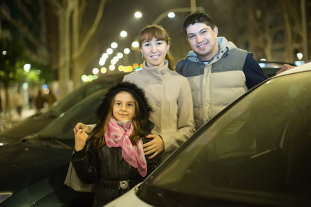 Happy family with girl posing near car outdoors in winterの写真素材