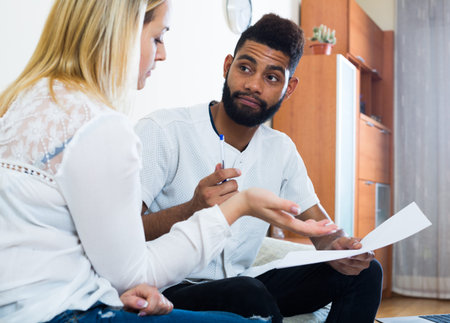 Interracial family couple filling papers for mortgage indoors