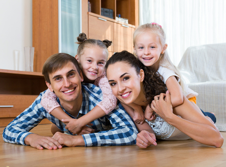 Family values: portrait of positive european parents with little girls indoorsの写真素材