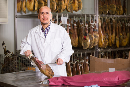 Salesman cutting jamon on slices in delicatessen storeの写真素材