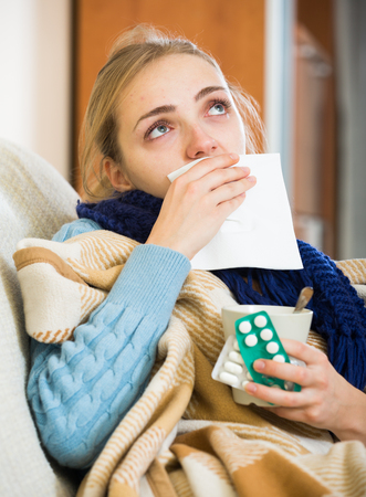 Young woman with cold and blocked nose at homeの写真素材