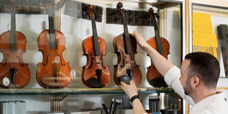 Positive man with beard purchasing traditional violins in store