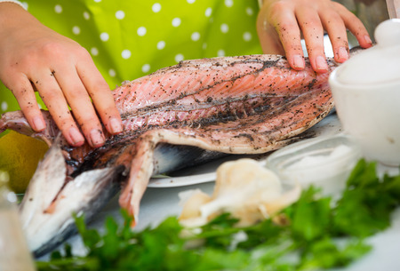 Female hands rubbing salt and pepper during pickling rainbow troutの写真素材